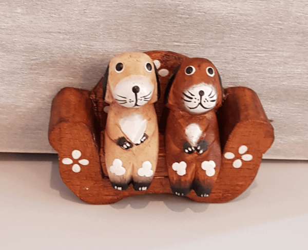 2 hand painted wooden dogs sat on a sofa