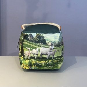 classic cube doorstop with a countryside scene , cute cottages, sheep and sheepdogs