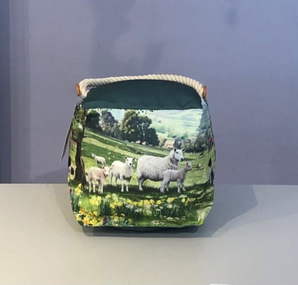 classic cube doorstop with a countryside scene , cute cottages, sheep and sheepdogs