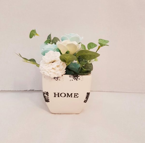Soap flowers in a white ceramic pot saying home
