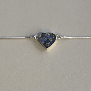 heart shaped charm filled with fright blue forget me nots on a silver snake bracelet