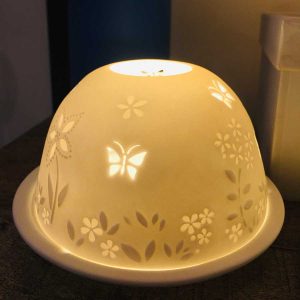 Dome tea light holder with a butterfly and flower design etched into its dome to create a stunning effect when it is lit from within